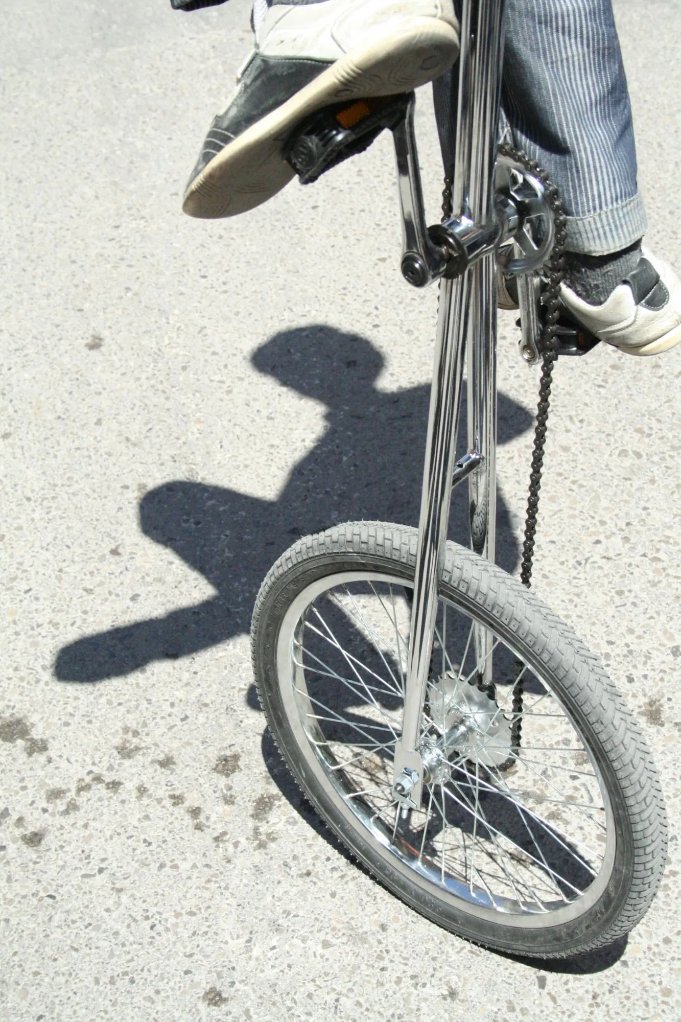 Bicicleta alta cromada y su sombra sobre el asfalto al sol