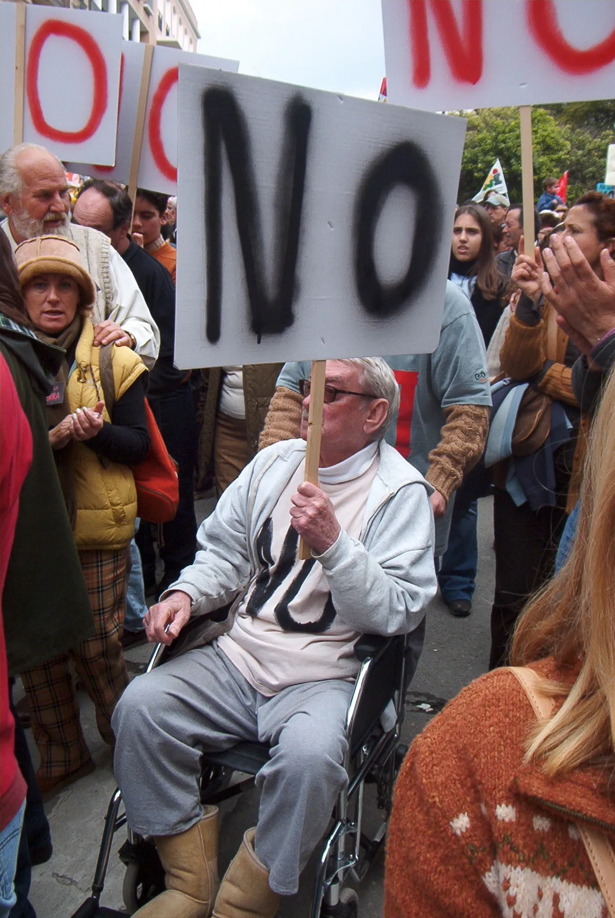 Hombre en silla de ruedas con una pancarta que dice NO en la manifestación contra la guerra de Irak de 2003
