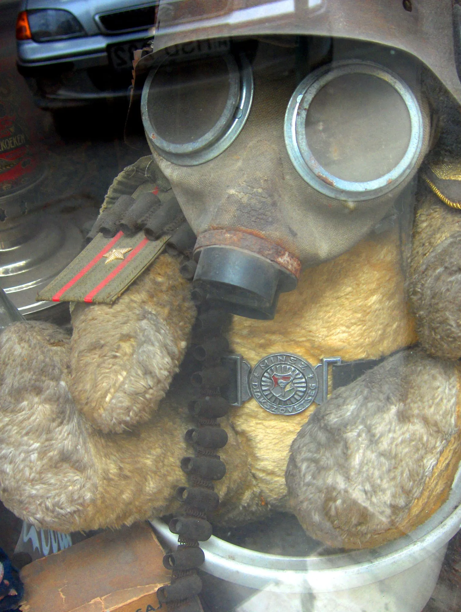 Oso de peluche antiguo con máscara de gas y charreteras militares en un escaparate de Budapest