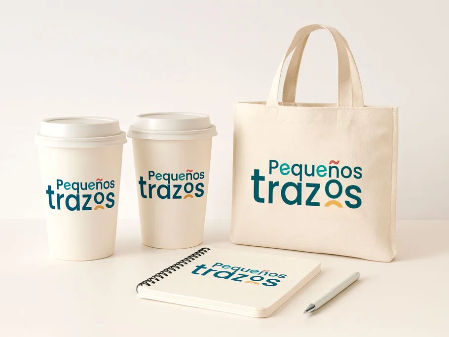 Logotipo de Pequeños Trazos en una bolsa de tela, vasos y una libreta