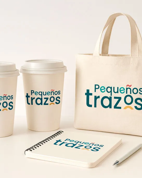 Logotipo de Pequeños Trazos en una bolsa de tela, vasos y una libreta