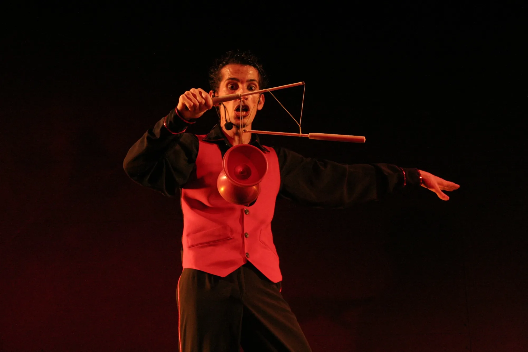 Malabarista con chaleco rojo haciendo girar un diábolo sobre fondo rojo
