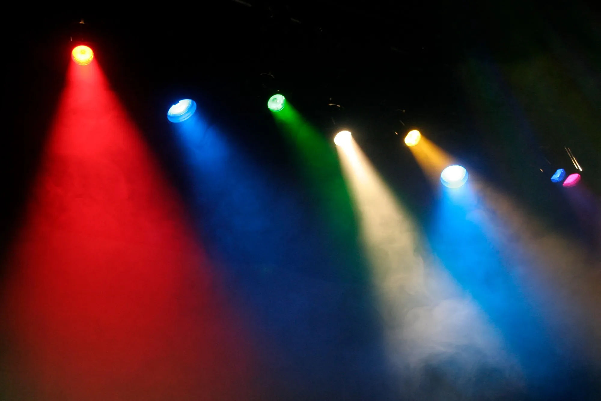 Focos de colores rojo, azul, verde y amarillo atravesando el humo del escenario