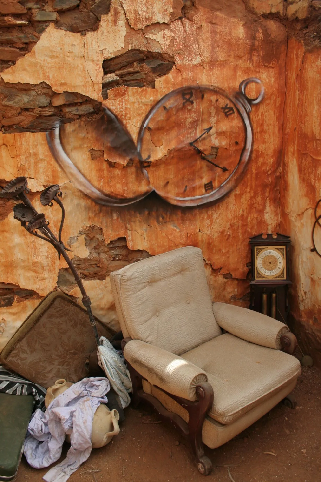 Sillón viejo ante una pared desconchada con un reloj de bolsillo pintado