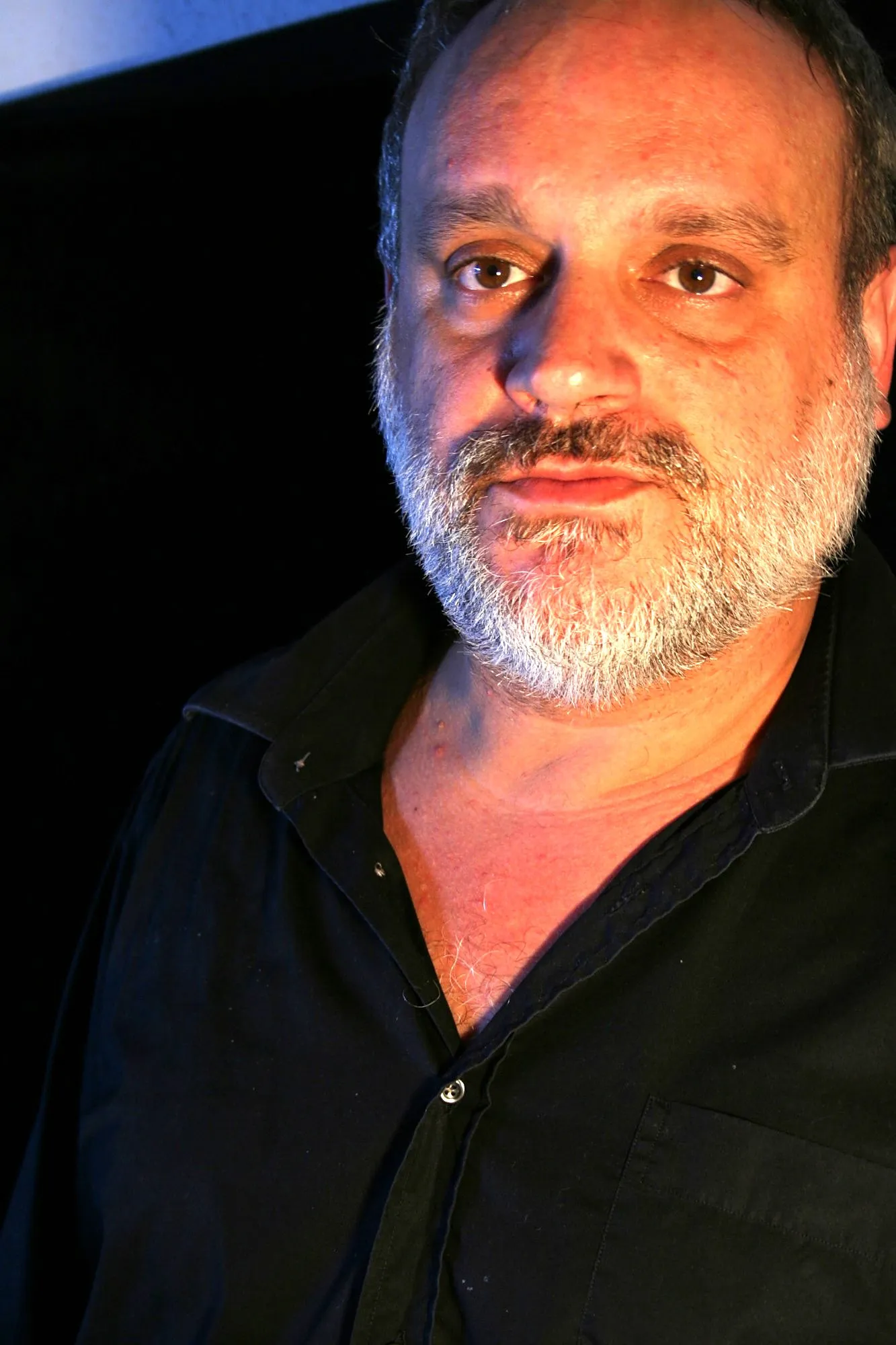 Actor de Granit con barba gris y camisa negra mirando a cámara