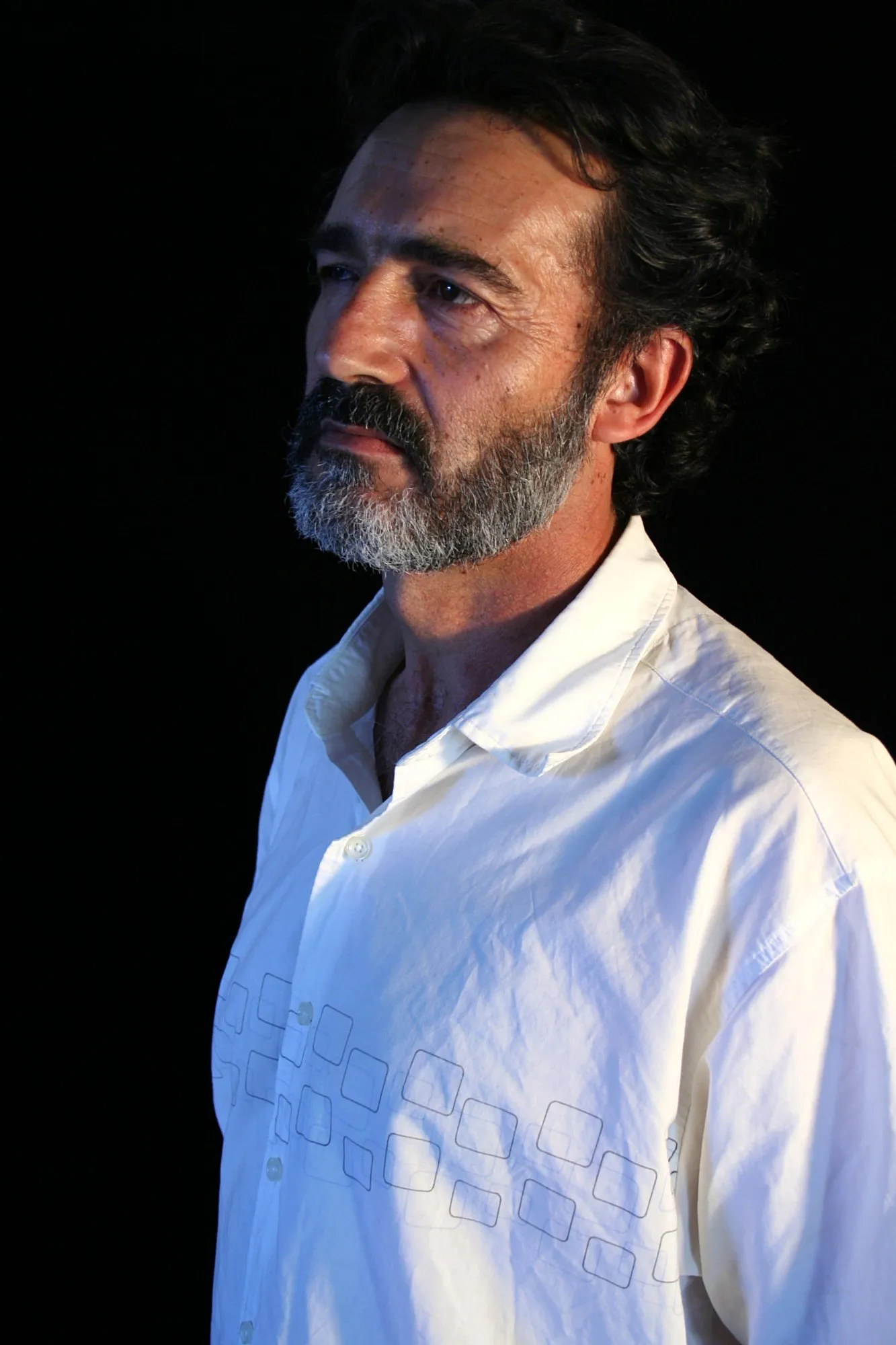 Actor de Granit con barba canosa y camisa blanca, de tres cuartos y mirando a lo lejos