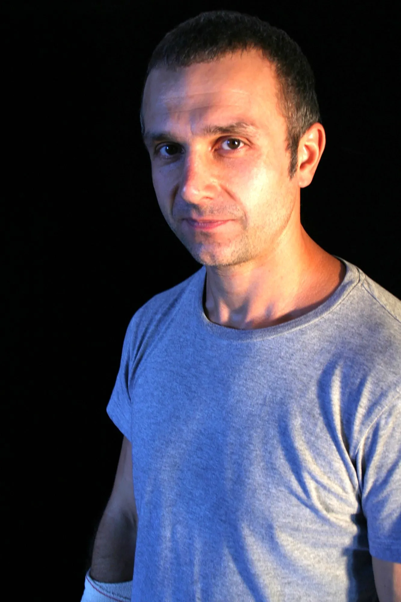 Actor de Granit con el pelo corto y camiseta gris, con media sonrisa