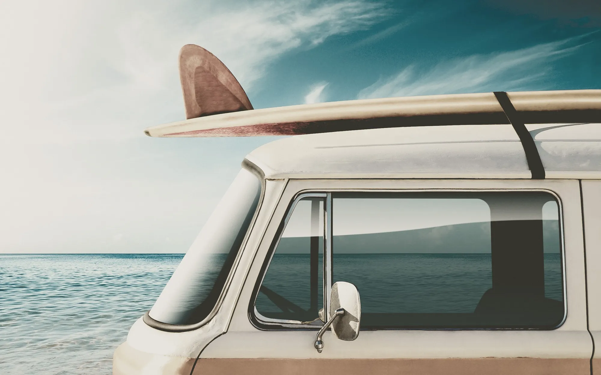 Furgoneta clásica con una tabla de surf en el techo aparcada frente al mar