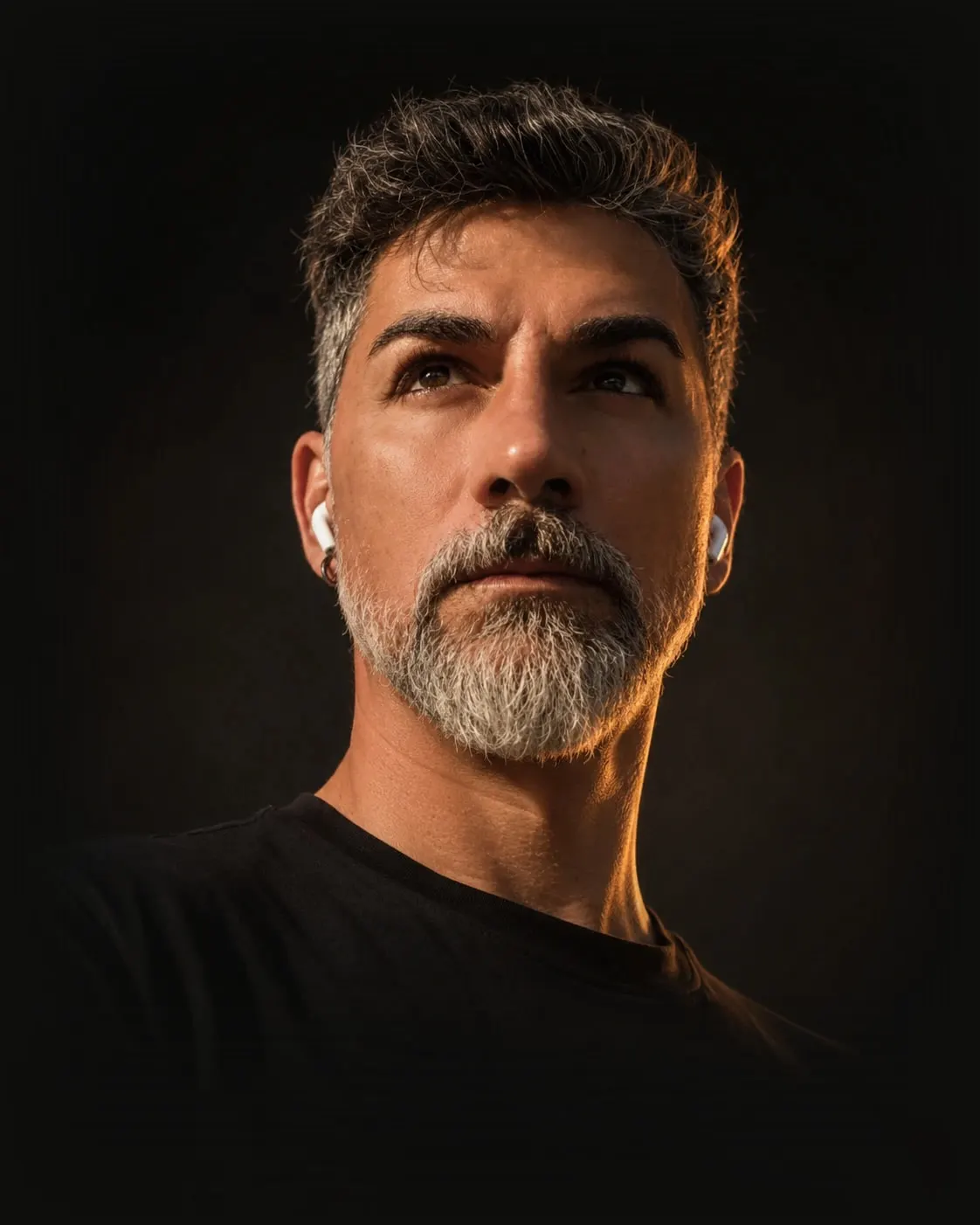 Retrato de Momi Cohen con camiseta negra, iluminado con luz cálida sobre fondo oscuro