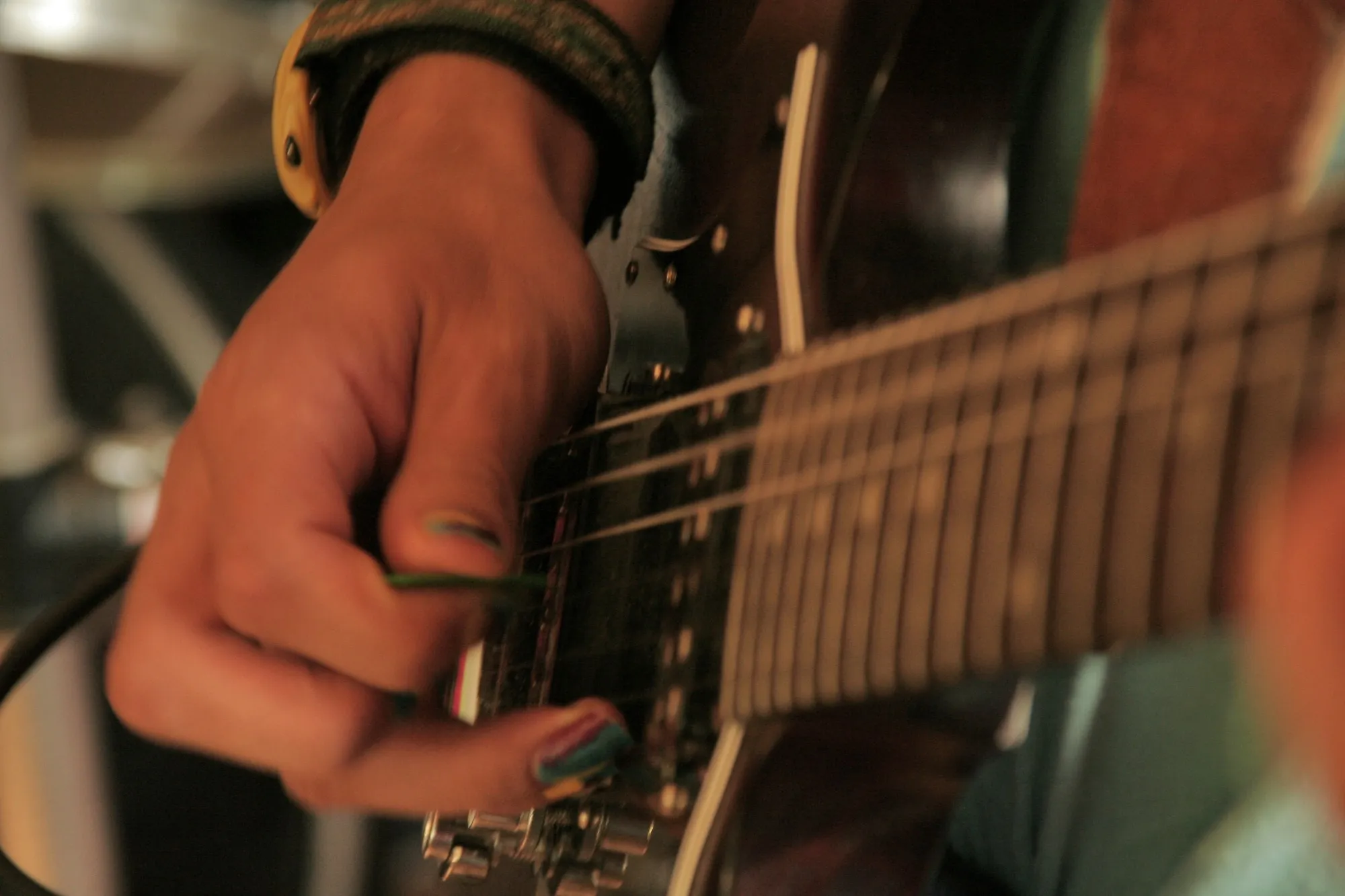 Primer plano de una mano tocando una guitarra eléctrica con púa