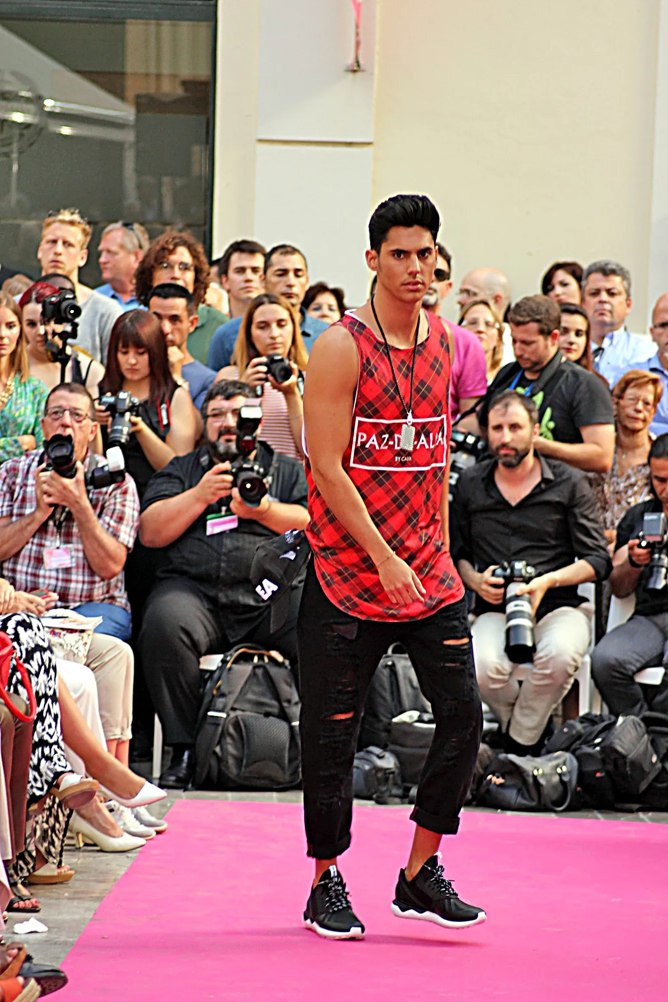 Modelo con camiseta de tirantes de cuadros rojos y vaqueros negros rotos, ante los fotógrafos