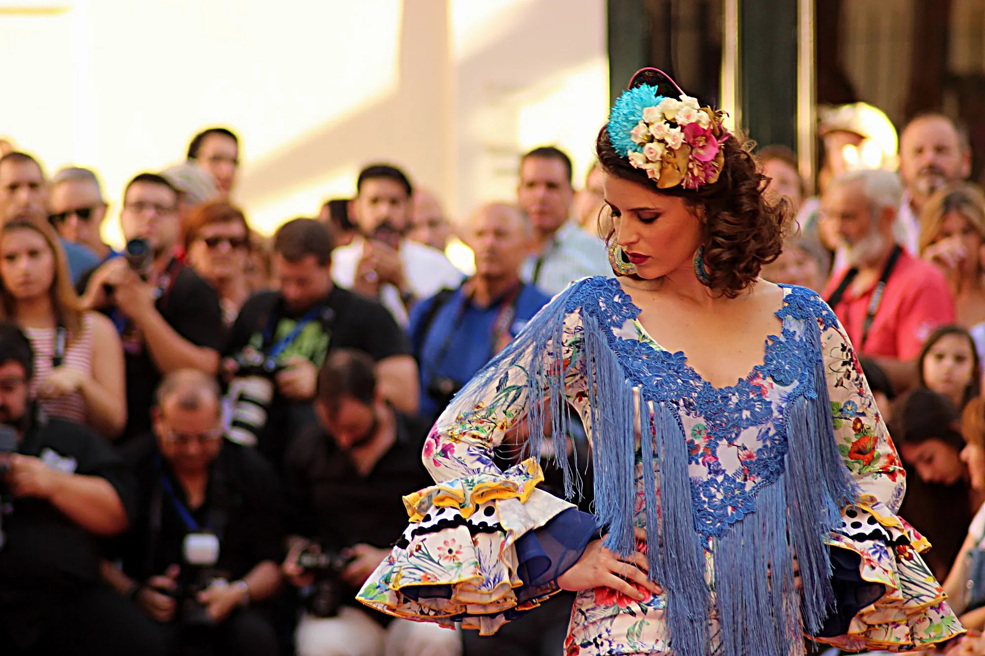 Modelo con traje de flamenca de flores, mantón de flecos azules y flores en el pelo, ante los fotógrafos
