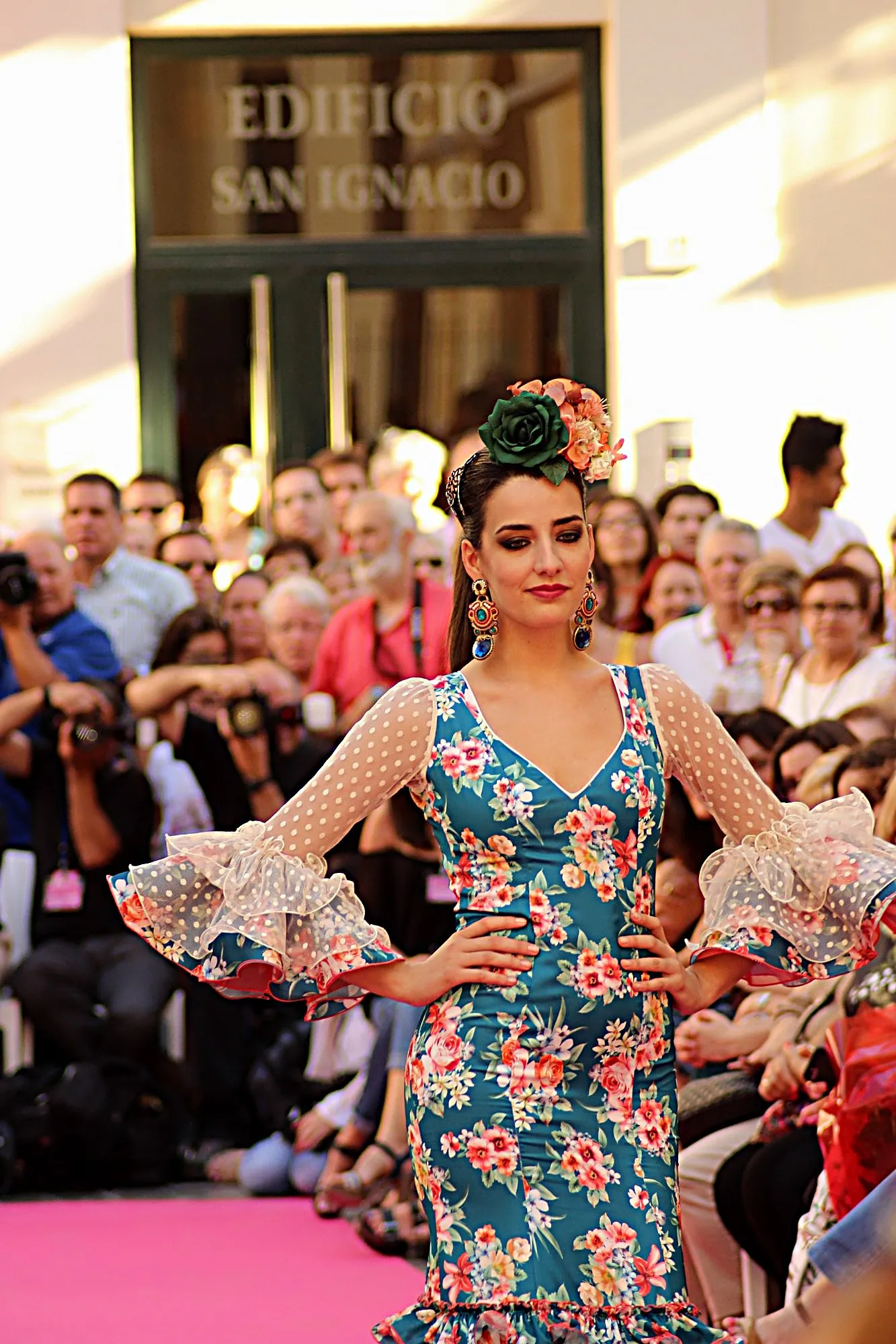 Modelo con traje de flamenca azul de flores y mangas de tul de lunares, con las manos en la cintura