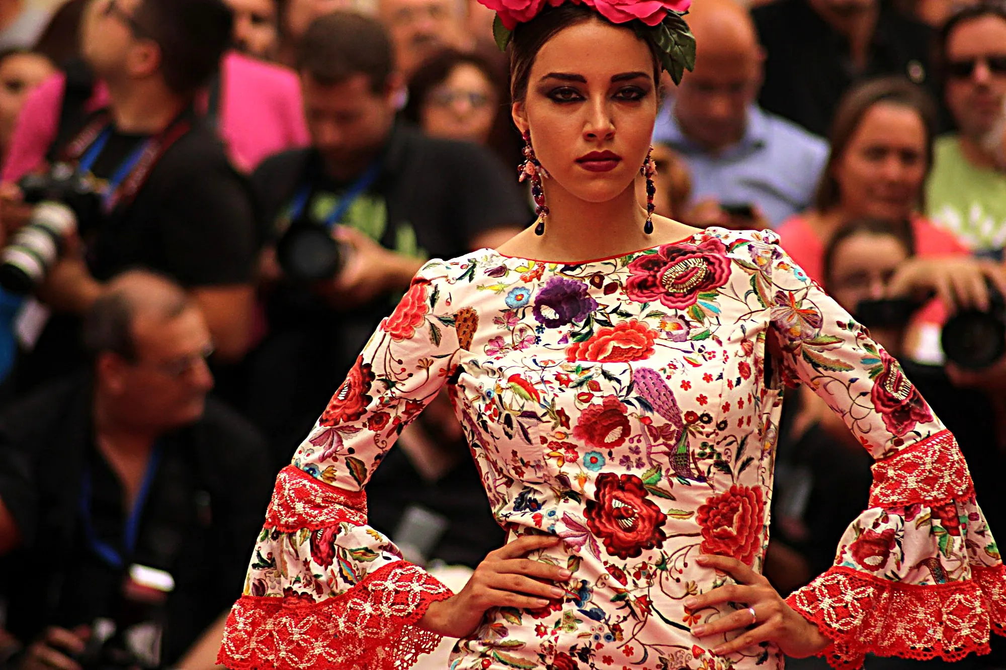 Modelo con traje de flamenca estampado de mantón de Manila y volantes de encaje rojo, con las manos en la cintura