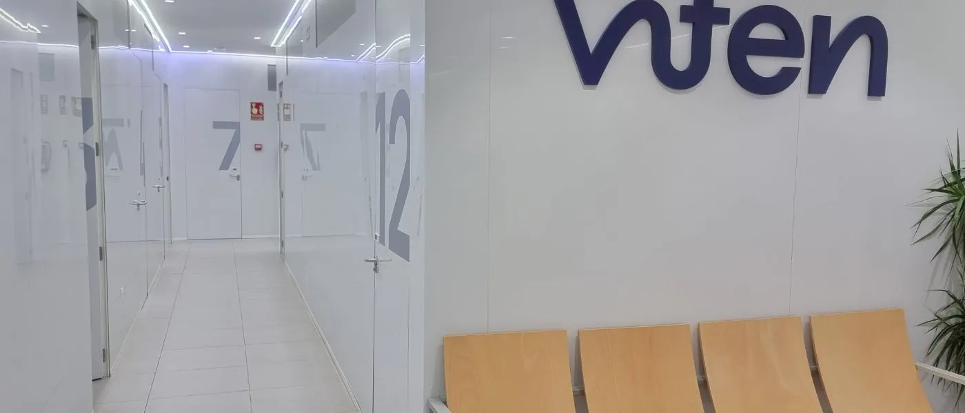Pasillo de consultas de Viten con el logotipo corpóreo en azul sobre la pared y una bancada de madera