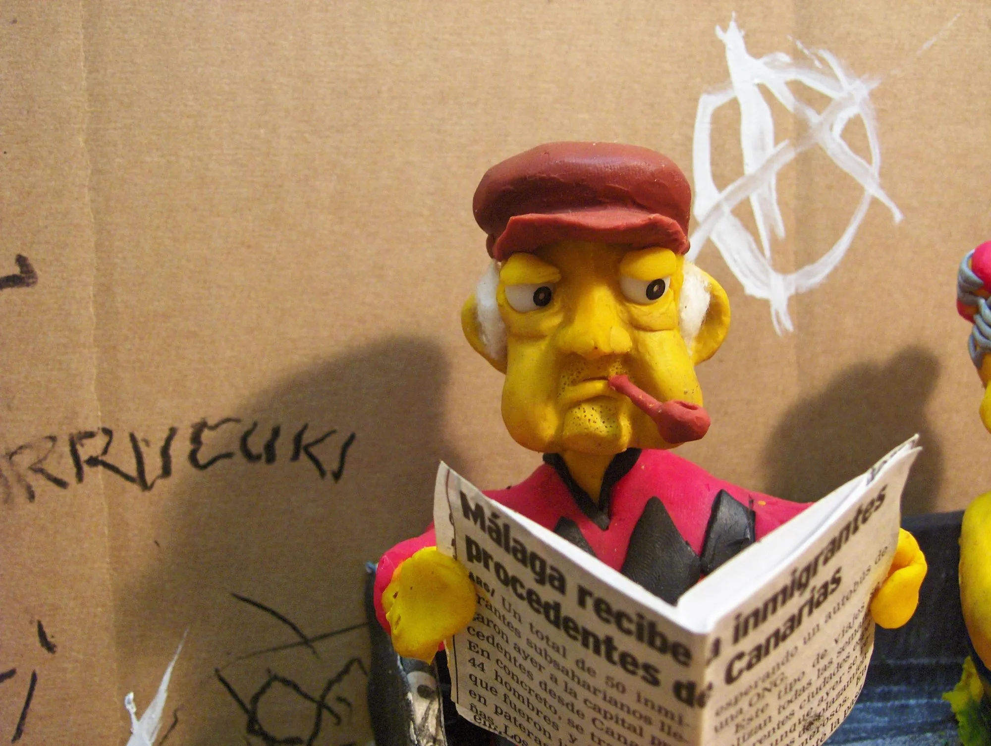 Anciano de plastilina con pipa leyendo un periódico en miniatura
