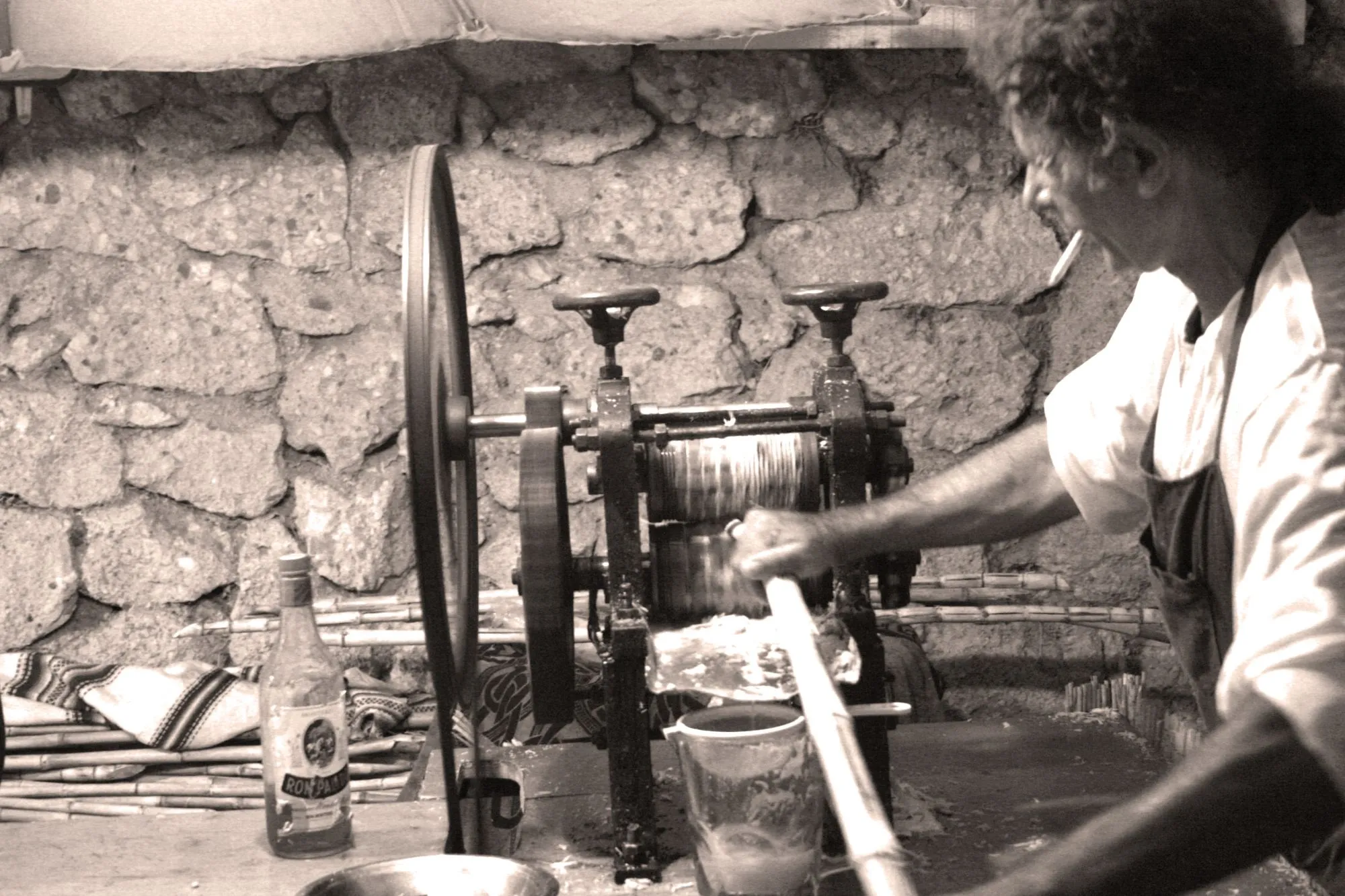 Hombre prensando caña de azúcar en un trapiche antiguo, en sepia