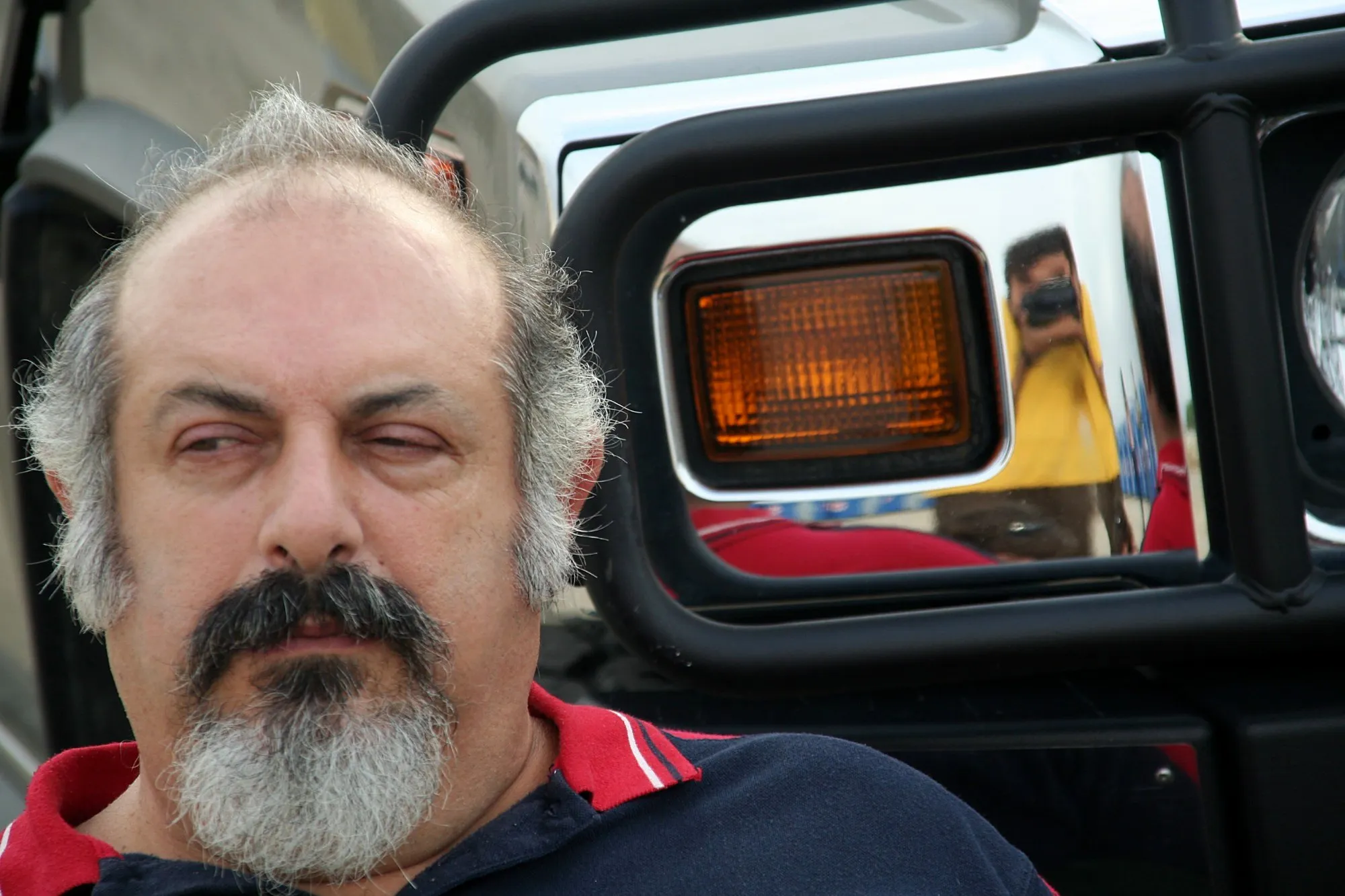 Operador de cámara reflejado en el tapón cromado del depósito de un coche