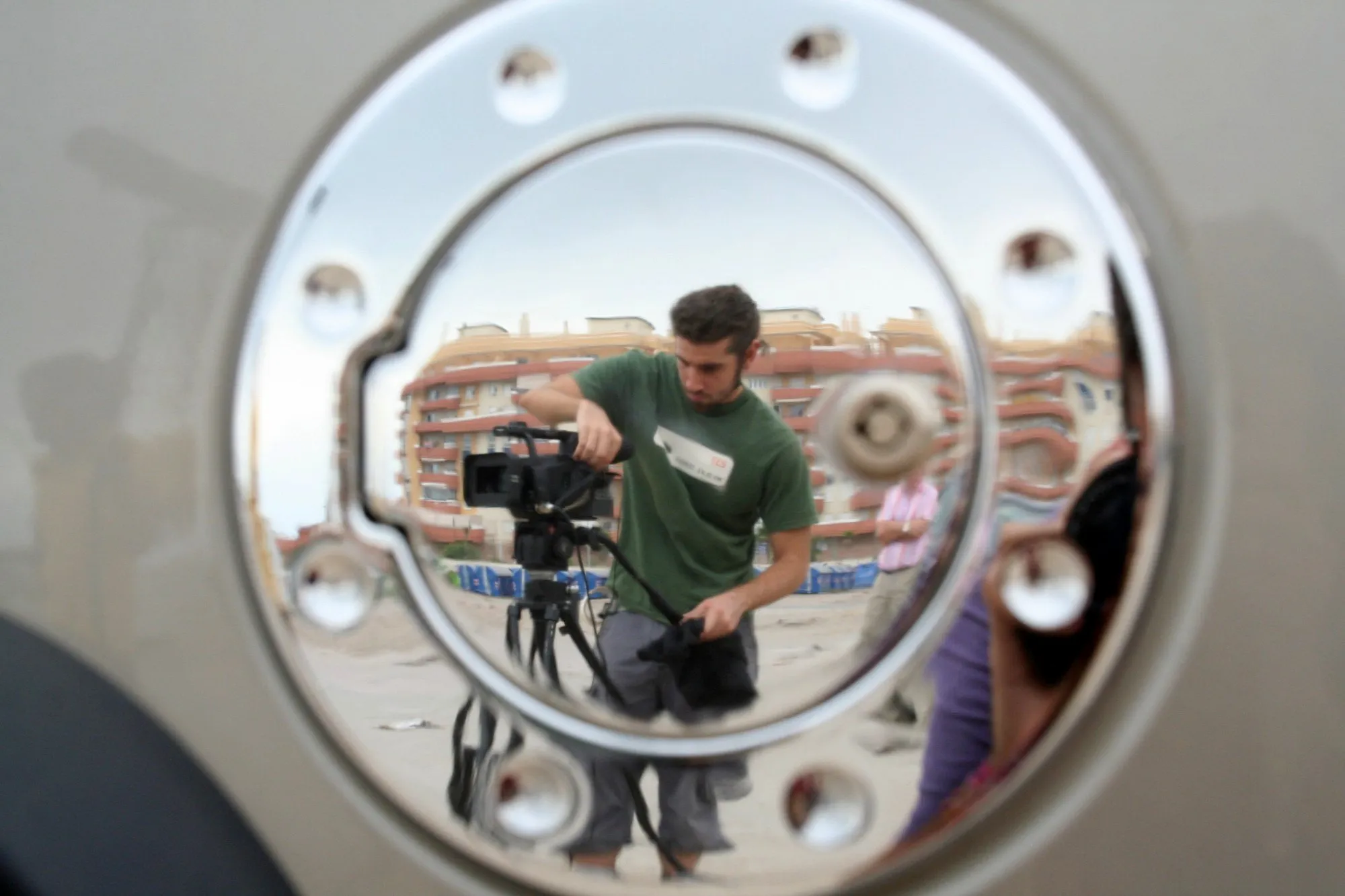 Actor con perilla junto al faro de un todoterreno, en cuyo cromado se refleja el fotógrafo