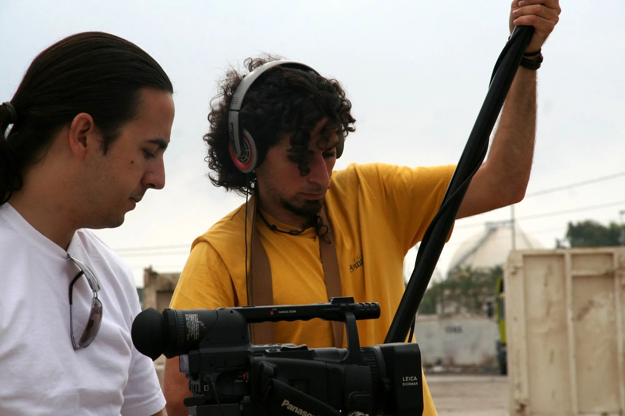 Técnico de sonido con cascos y pértiga junto al director, detrás de la cámara