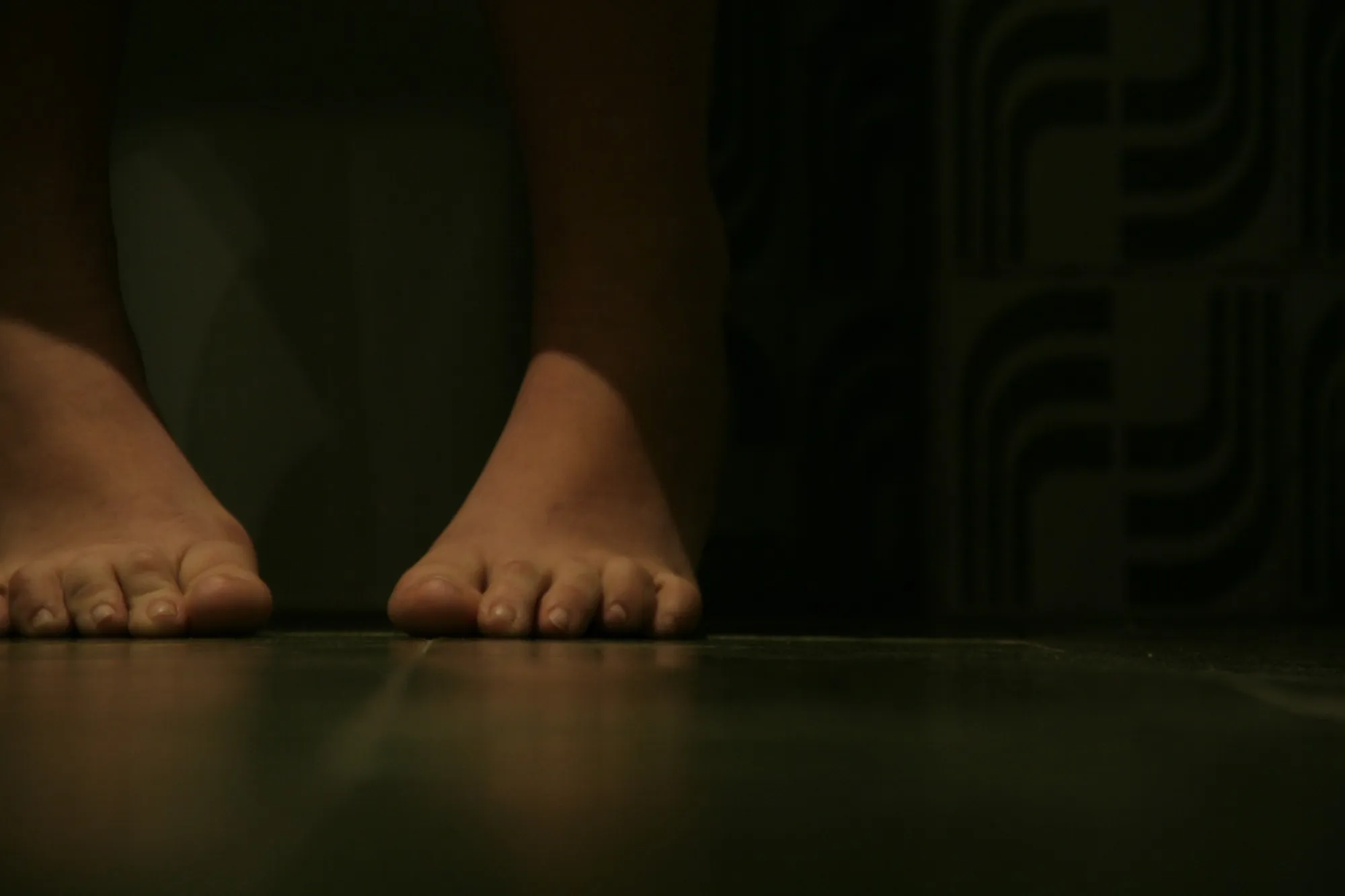 Pies descalzos sobre un suelo oscuro a ras de suelo