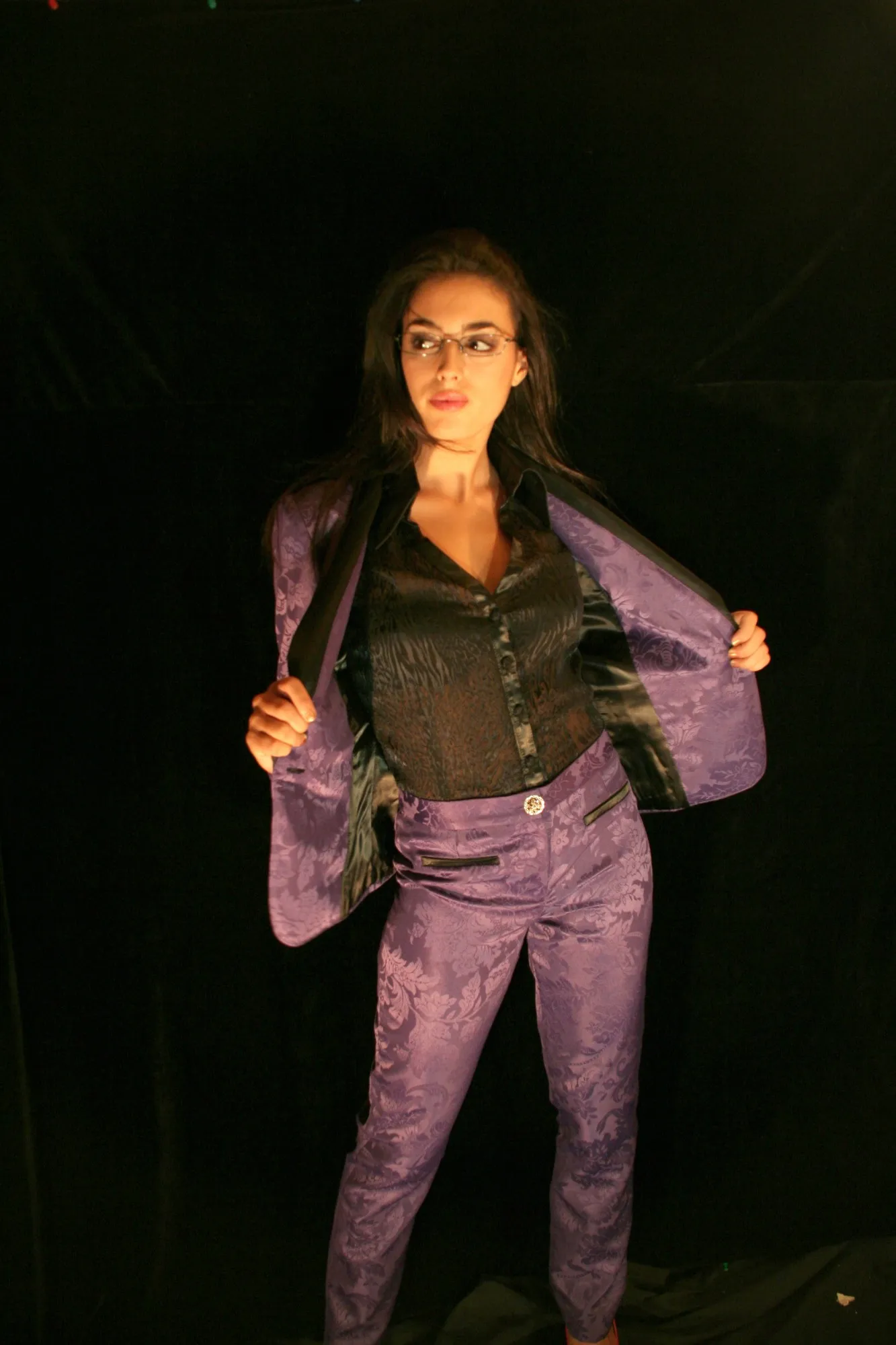 Modelo con gafas abriendo una chaqueta de jacquard morado a juego con el pantalón