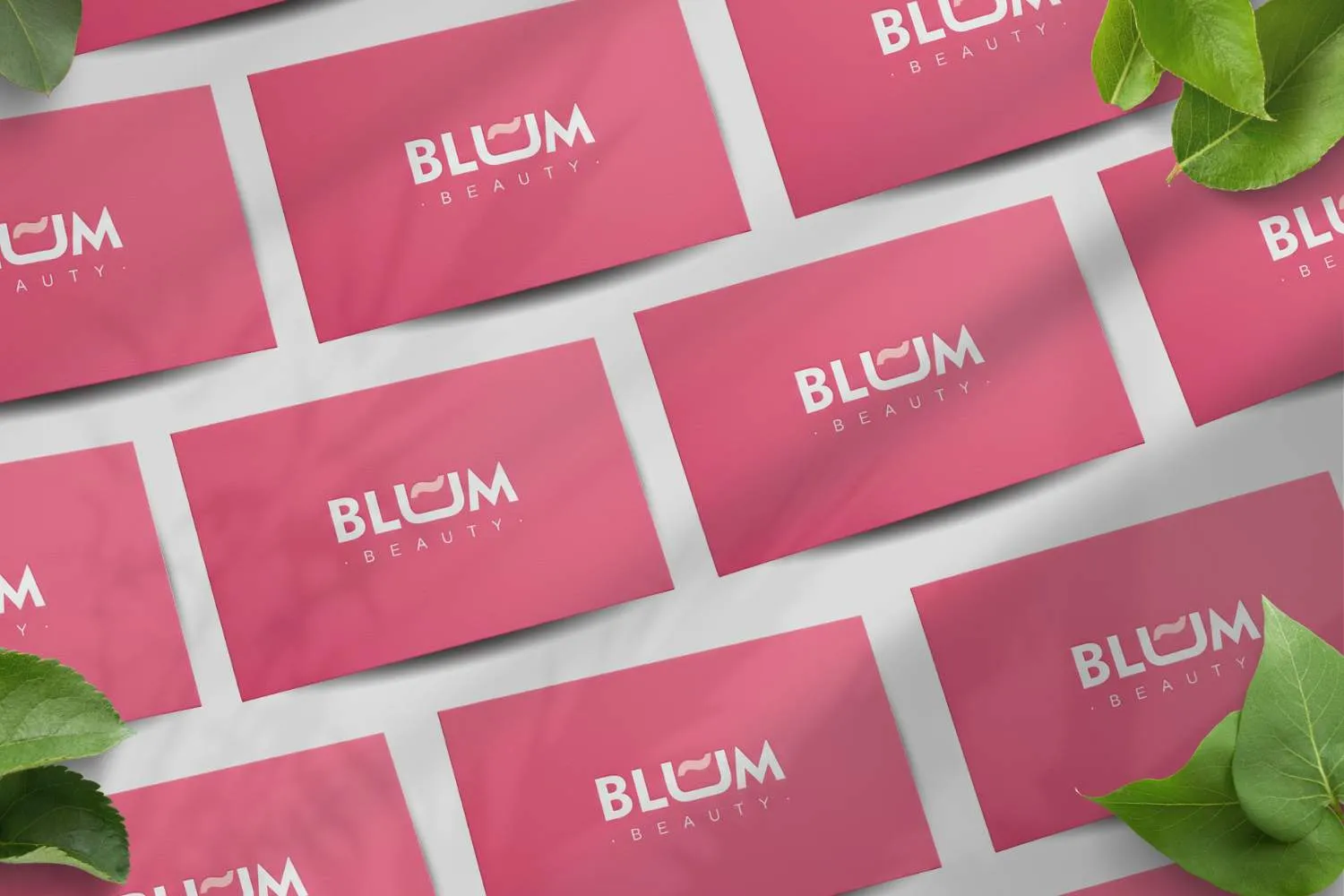 Tarjetas de visita rosas con el logotipo de Blum Beauty, rodeadas de hojas verdes