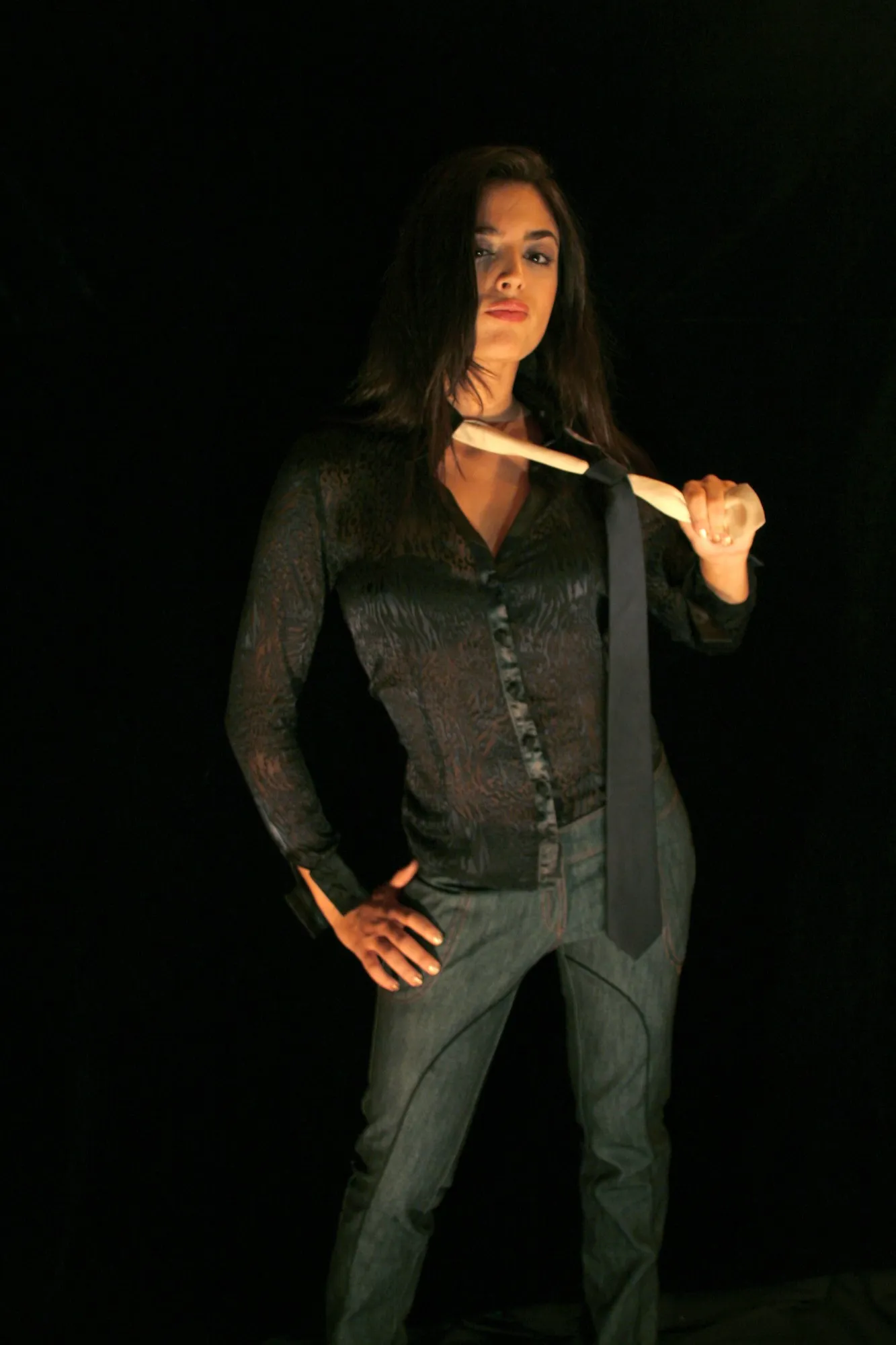 Modelo con camisa de encaje animal y corbata negra suelta, la mano en la cadera