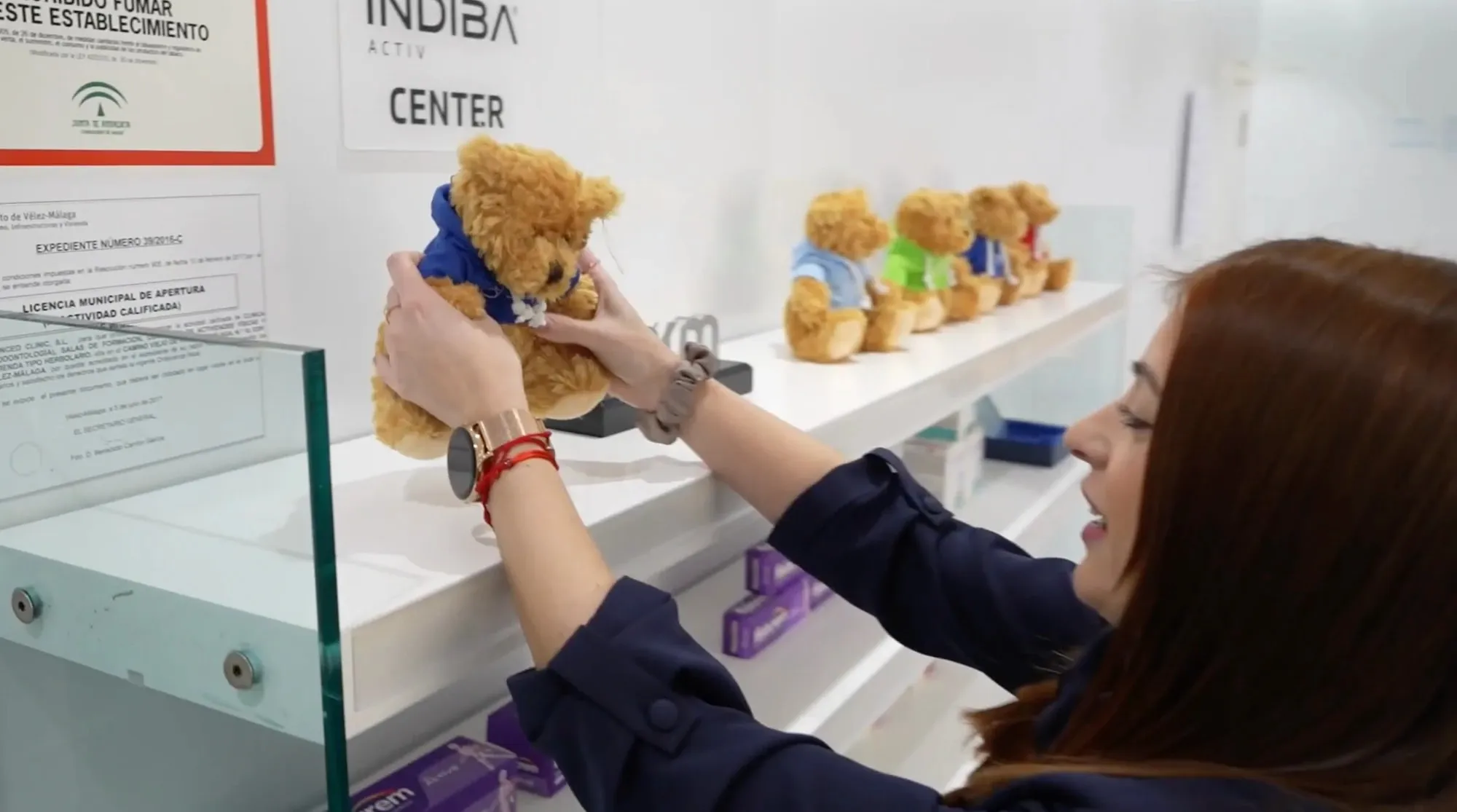 Una trabajadora de Viten colocando los peluches solidarios de Timoteo en una estantería de la clínica