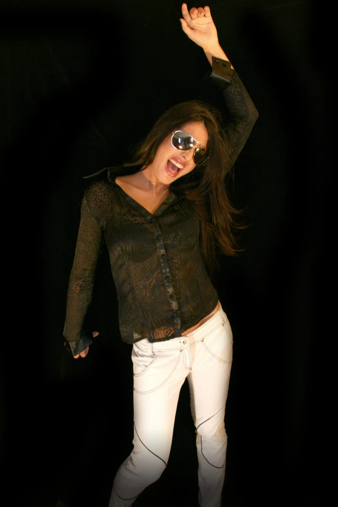 Modelo bailando con gafas de aviador, camisa de encaje animal y pantalón blanco