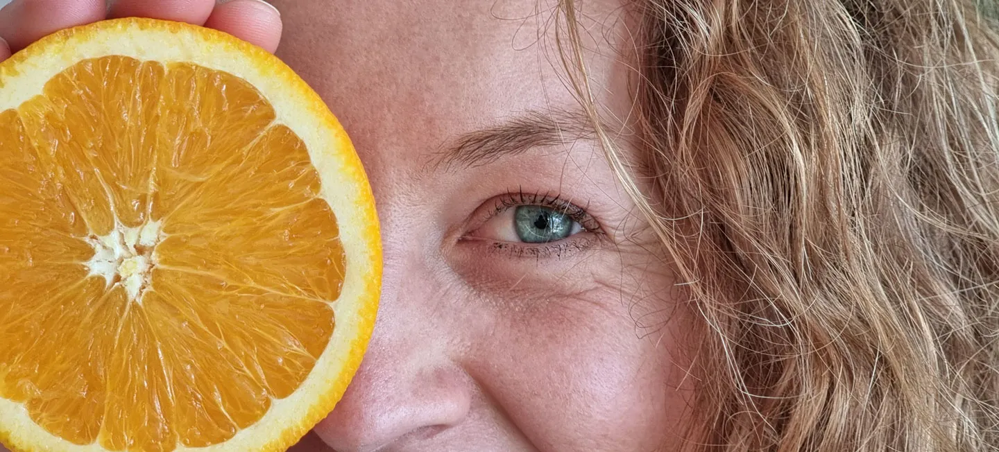 Primer plano con media naranja junto al rostro